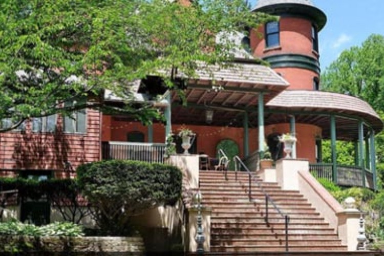 The stairs and front porch of The Castle, a private home in Hopewell. The house is red brick with green accents. There are trees on either side of the image.