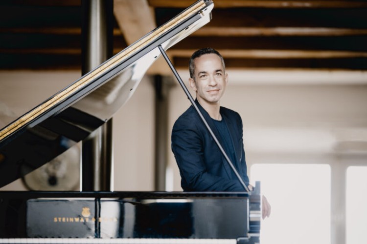 Pianist Inon Barnatan leans against a grand piano