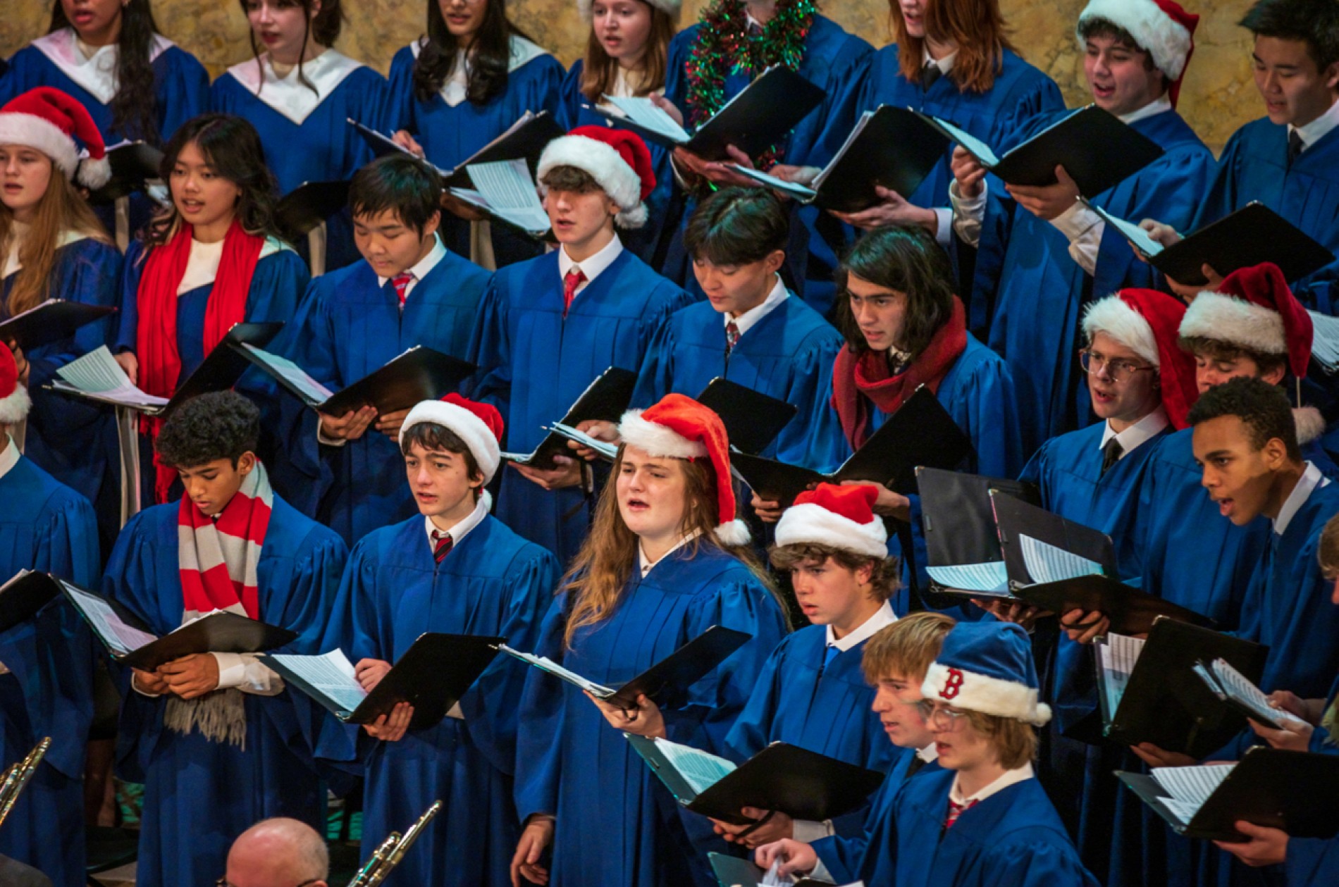 Choir members in blue robes and holiday hats and scarves at the 2022 Holiday POPS! concert