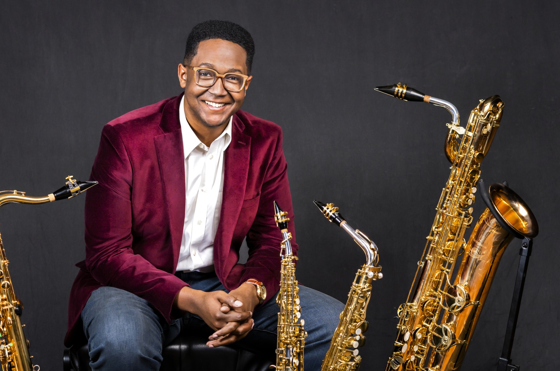 Steven Banks, saxophonist, sitting casually, surrounded by four types of saxophones